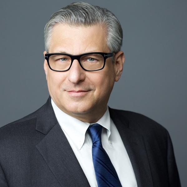 White male wearing a suite, tie and glasses